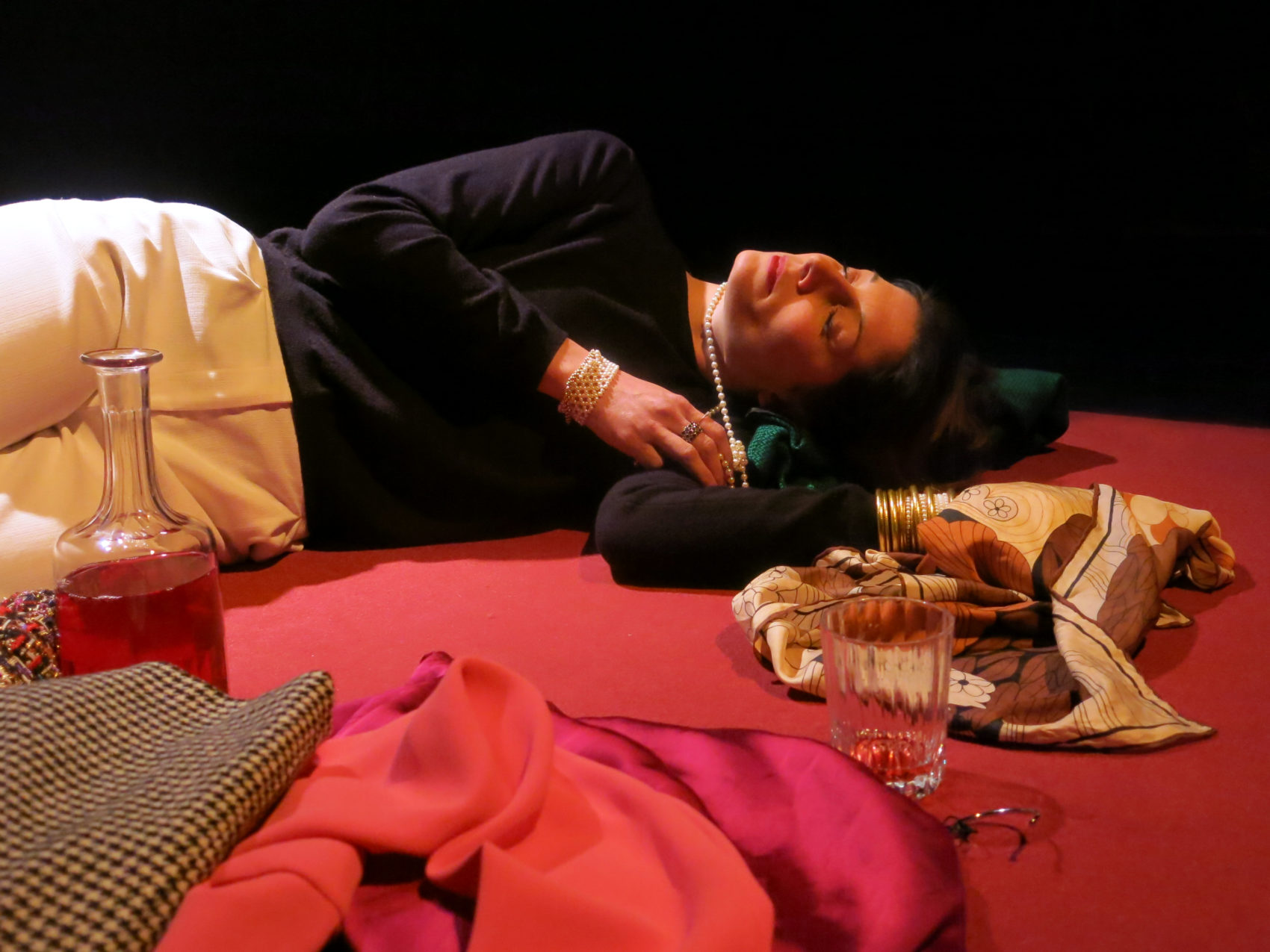 une femme allongée au sol avec un verre et une bouteille à coté 