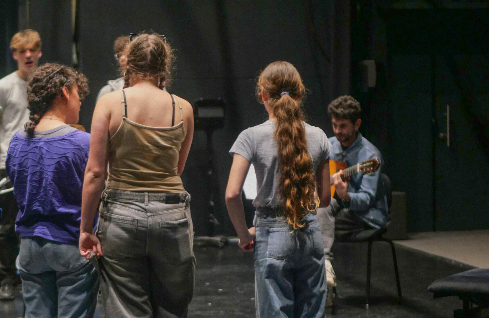 Photo répétition oda. avec des jeunes filles de dos et une guitariste au fond
