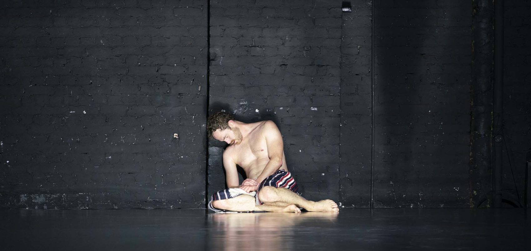 danseur à genoux sur scène, éclairé