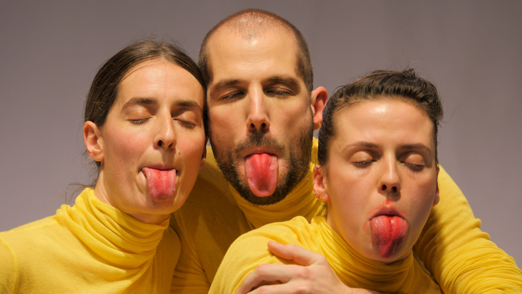 3 acteurs en pull jaune qui tirent la langue avec du rouge dessus 