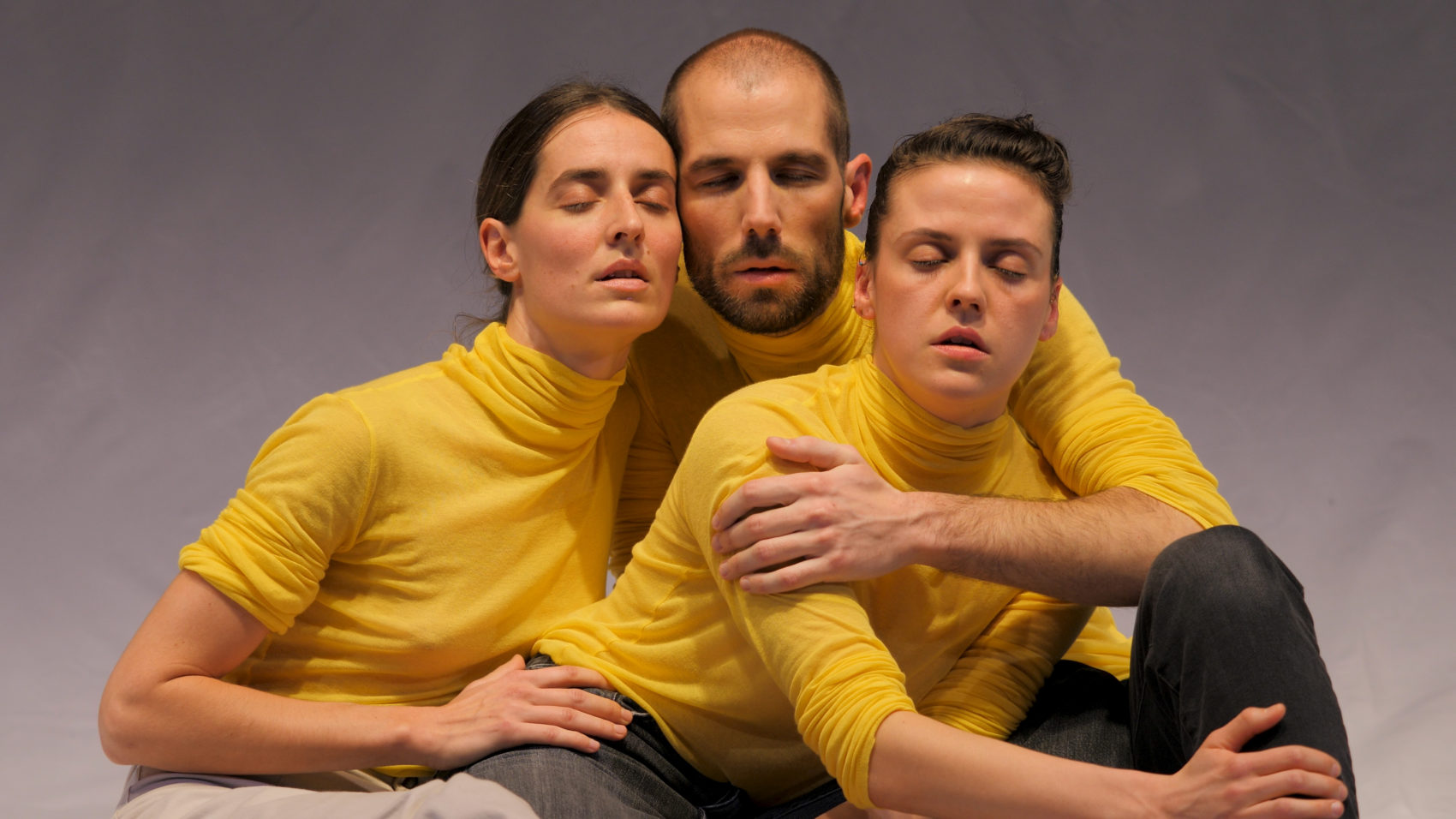 3 acteurs en pull jaune avec les yeux fermés
