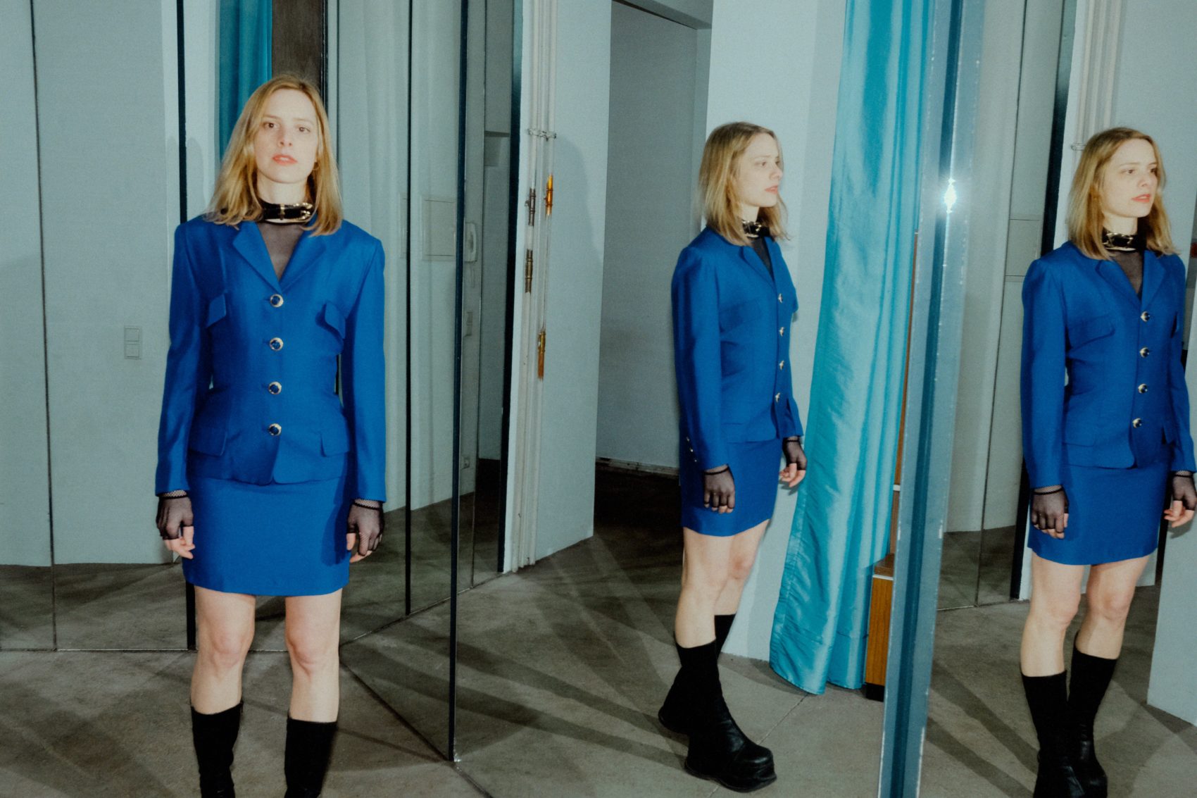 Anika en tailleur bleu avec son reflet en 2 fois dans des miroirs