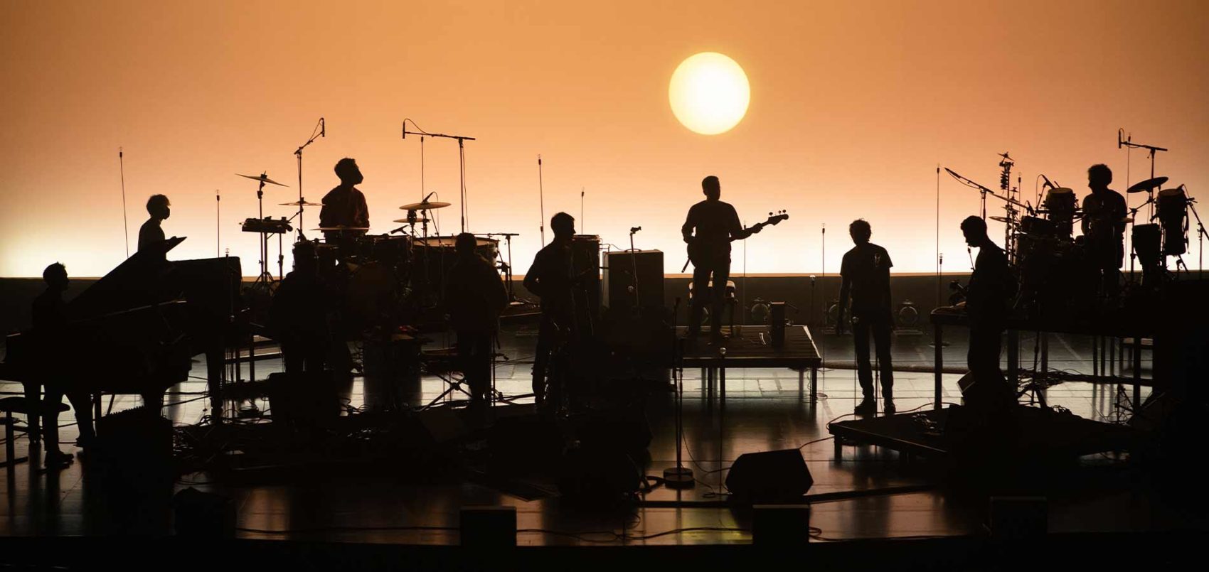 Phot sur scène de l'Orchestre du Tricot, un soleil en fond de scène