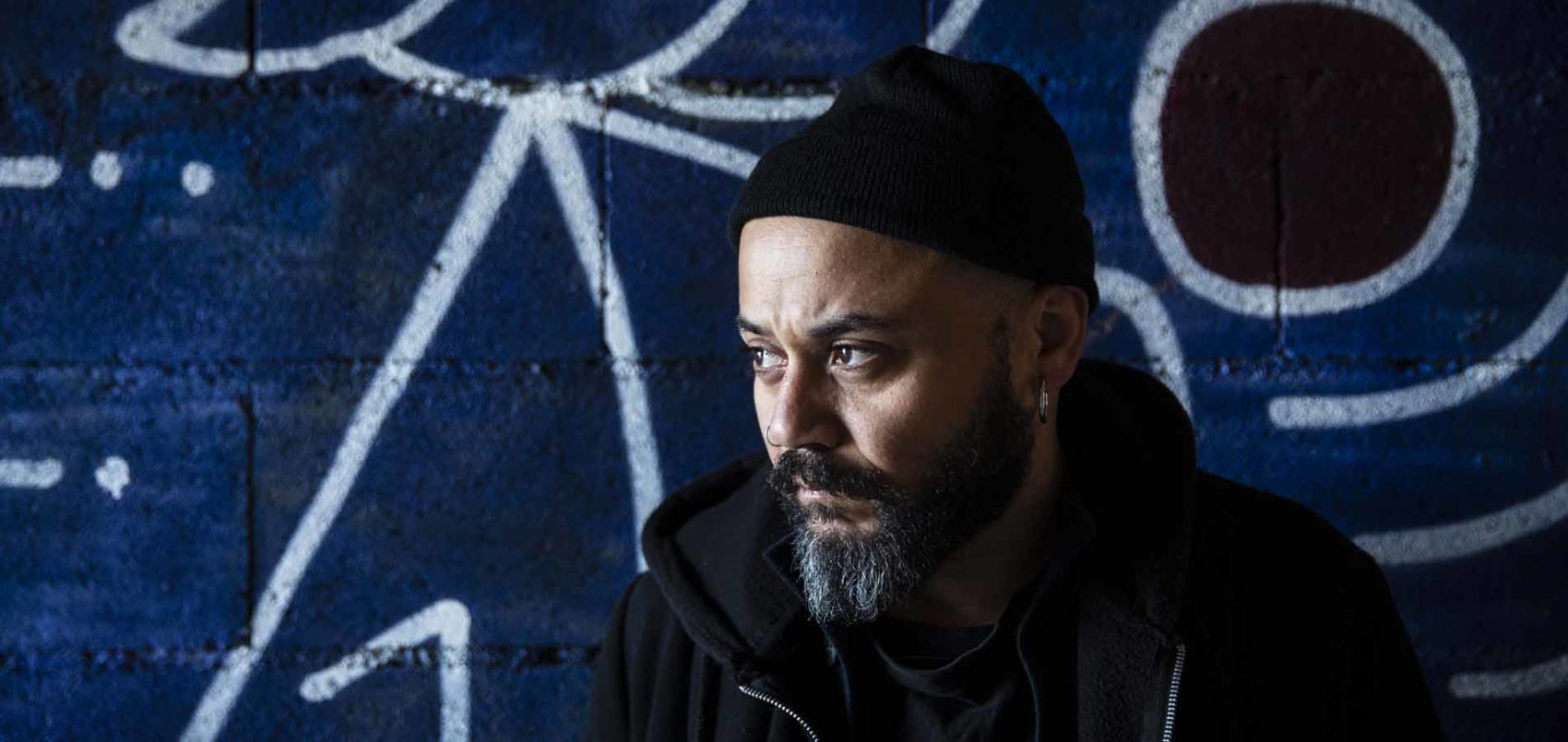 Portrait de Scuru Fitchadu, avec un sweat et un bonnet noir et une barbe 