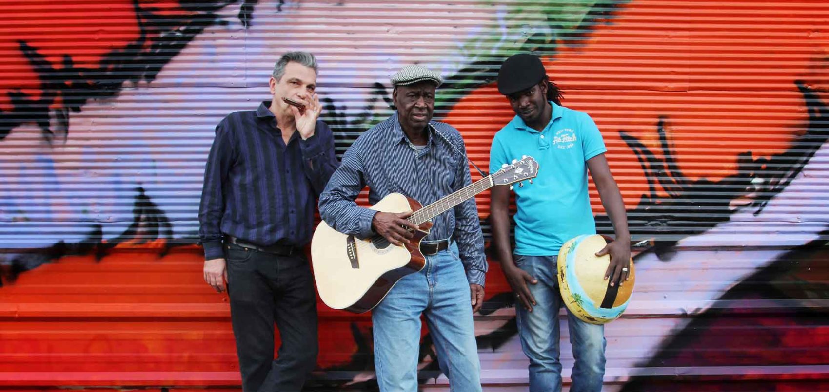 Boubacar Traoré est entouré de deux hommes, ils tiennent tous un instrument dans leurs mains