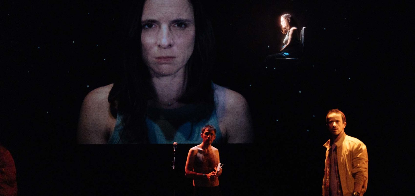 Sur scène, le portrait d'une femme projetée et une femme et un homme face au public 