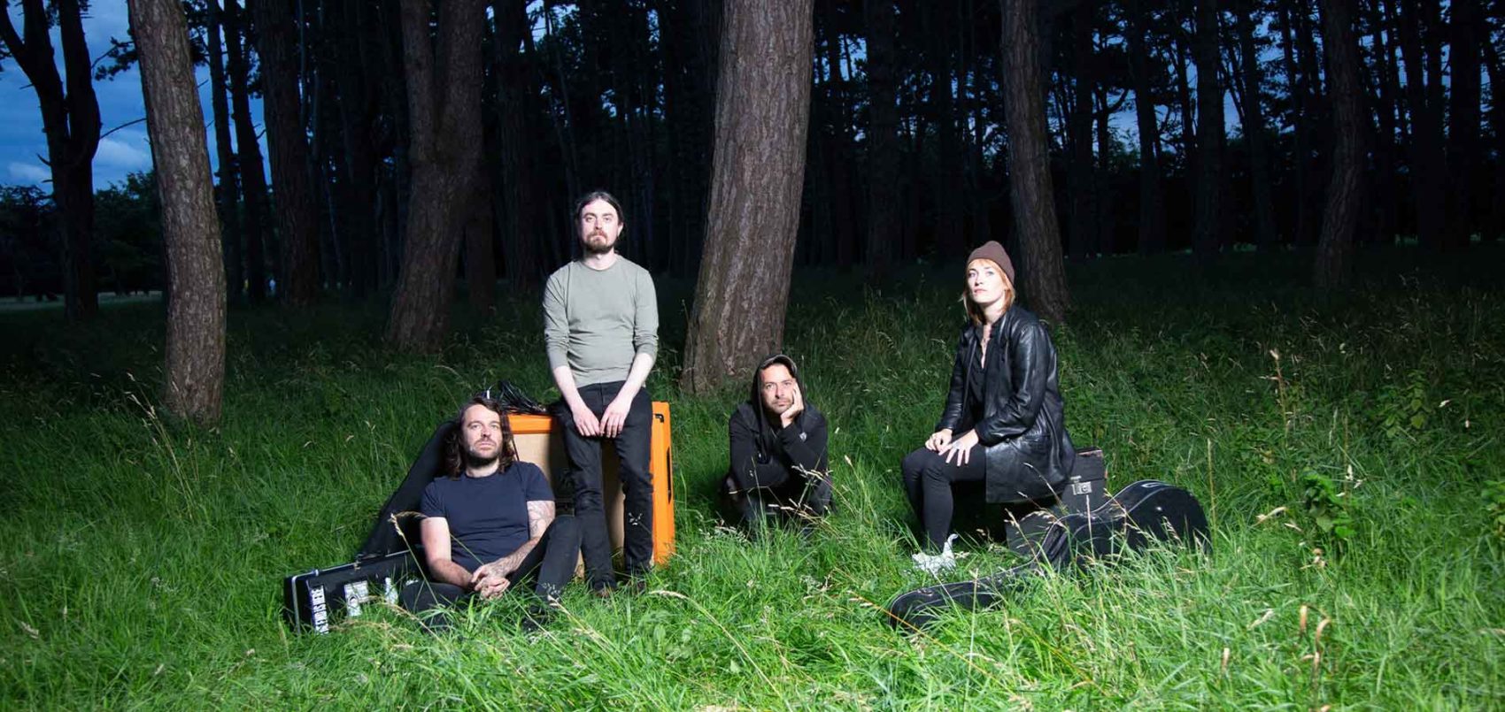 Quatre personnes sont assises dans l'herbe avec leurs instruments