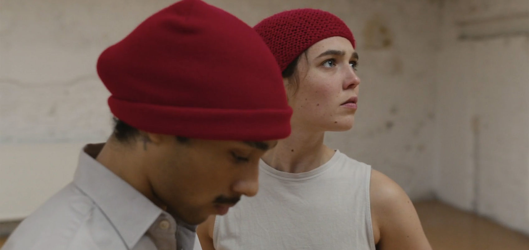Les deux danseurs, un homme et une femme, se tiennent l'un derrière l'autre. Ils portent des bonnets rouges. 