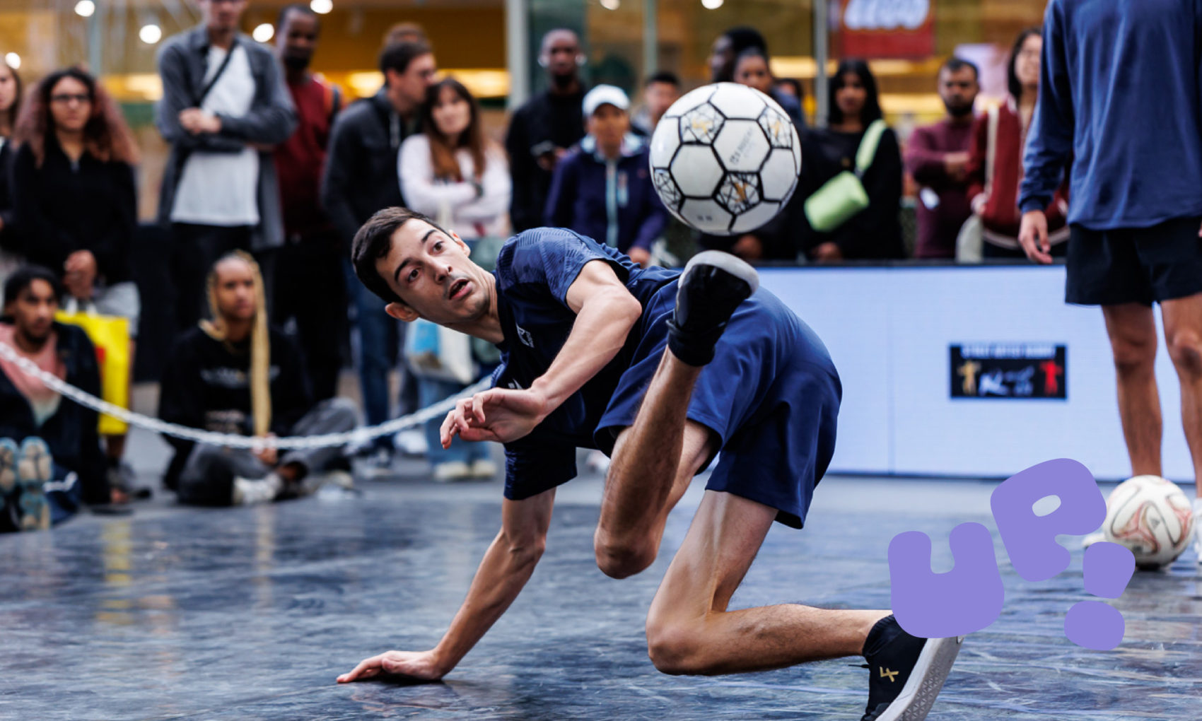 Une homme qui drible au sol avec un ballon de foot