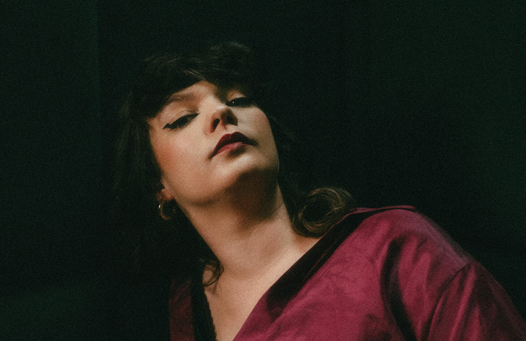 Portrait de Championne, sur un fond noir avec une chemise bordeaux