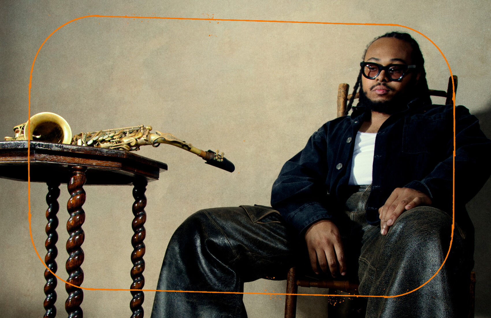 Photo de Immanuel Wilkins, assis sur une chaise avec un saxophone une une table devant lui