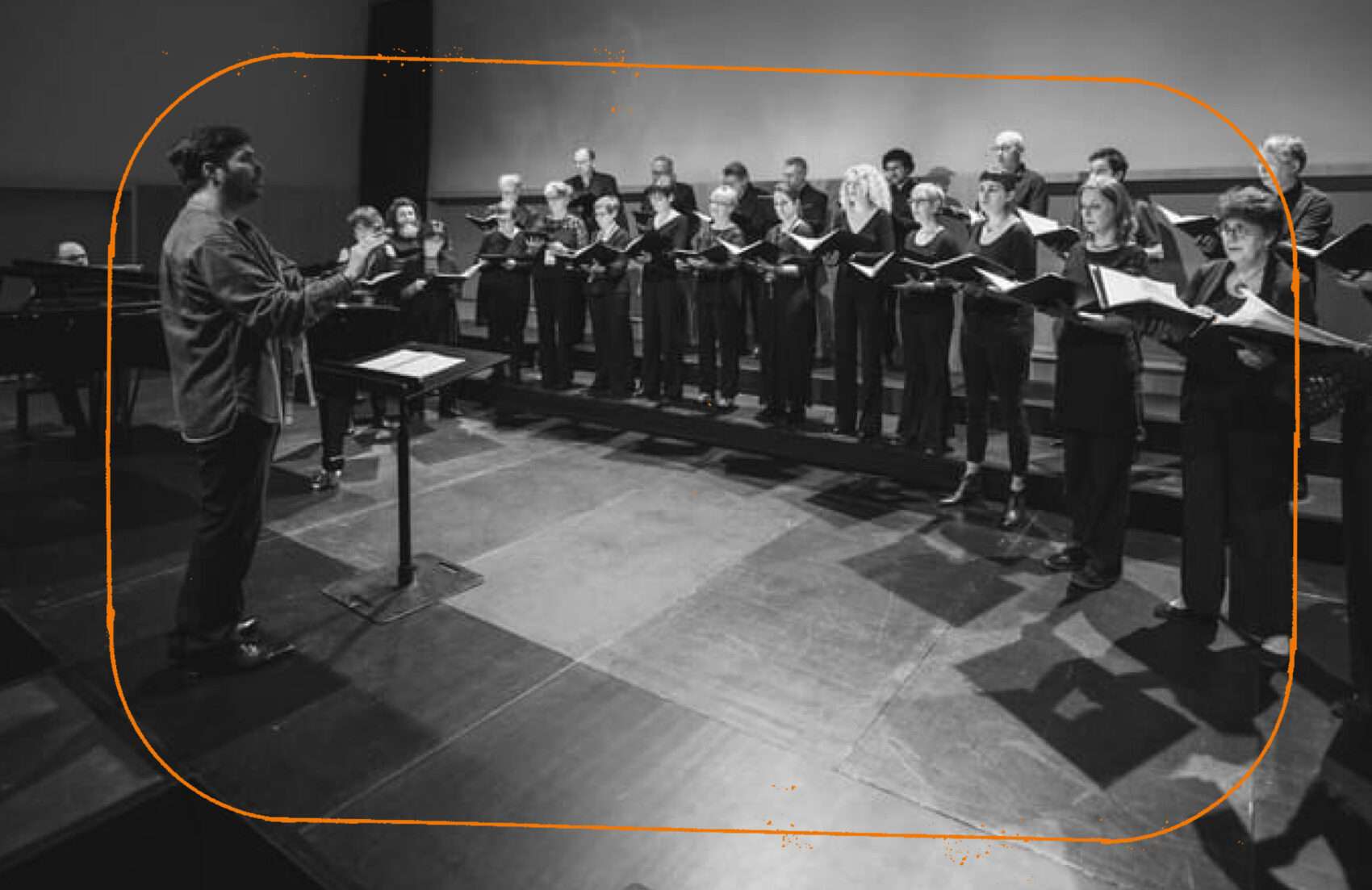 Photo en noir et blanc d'une chorale tenant leur partition et de leur chef de choeur. 