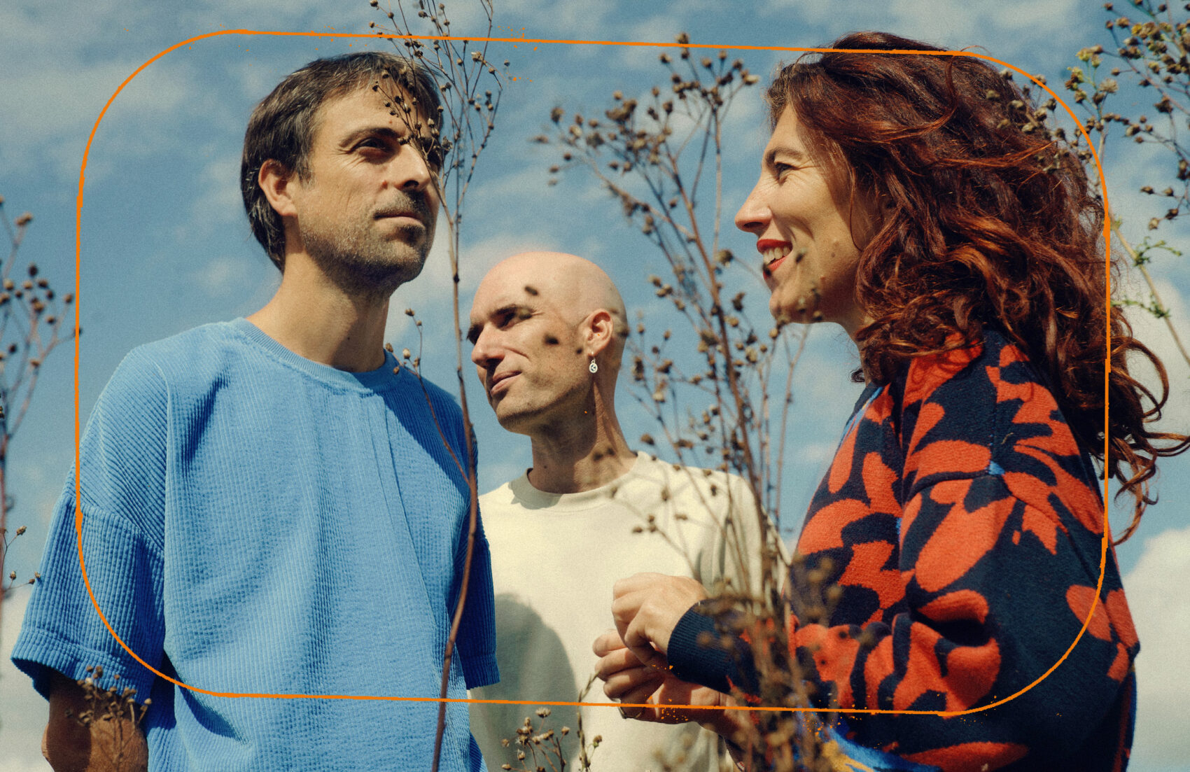 photo du trio Rouge avec deux homme et une femme avec le ciel en fond