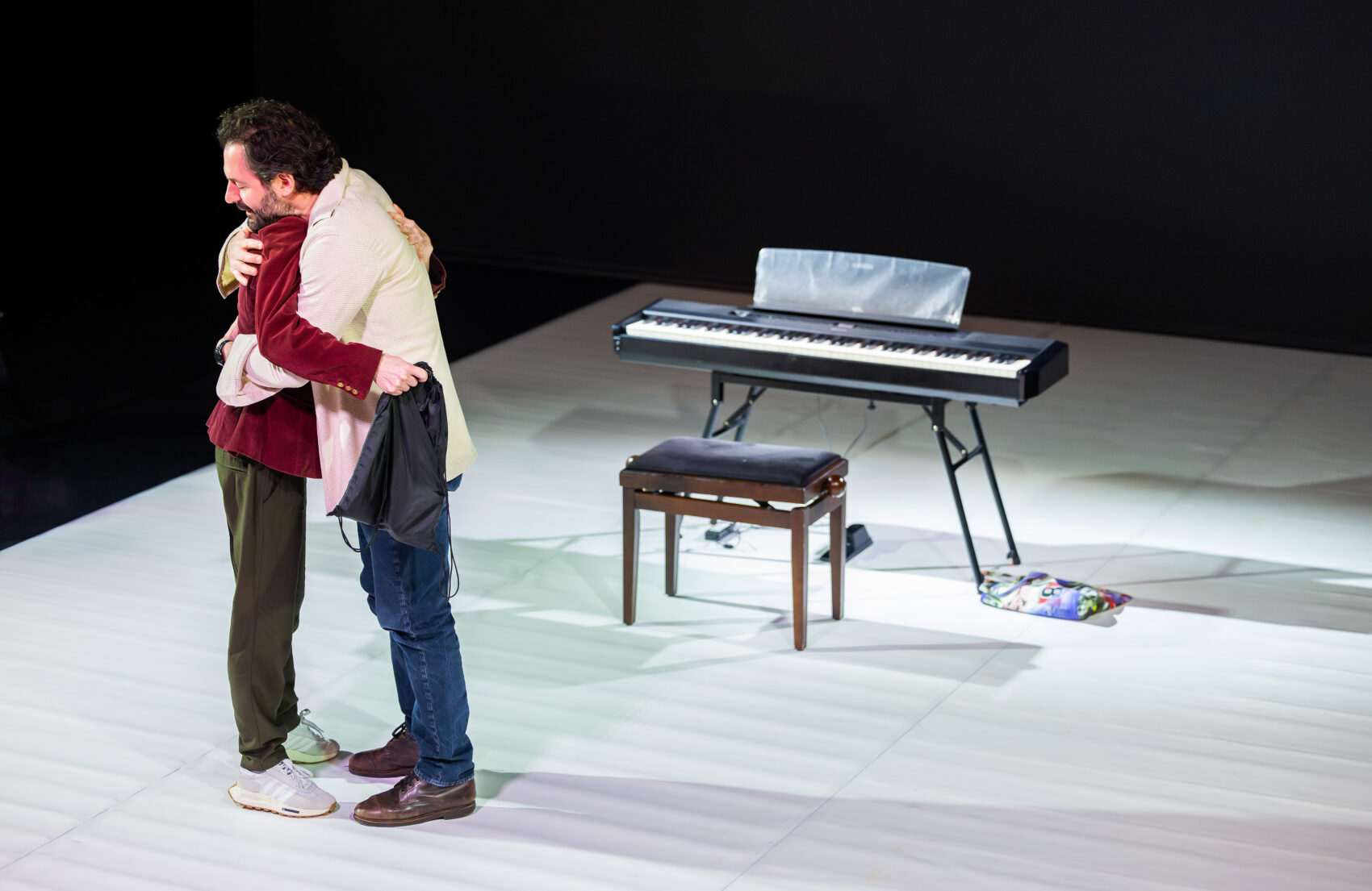 Photo de deux comédien, un homme et une femme qui s'enlace avec comme arrière plan un synthétiseuret son siège
