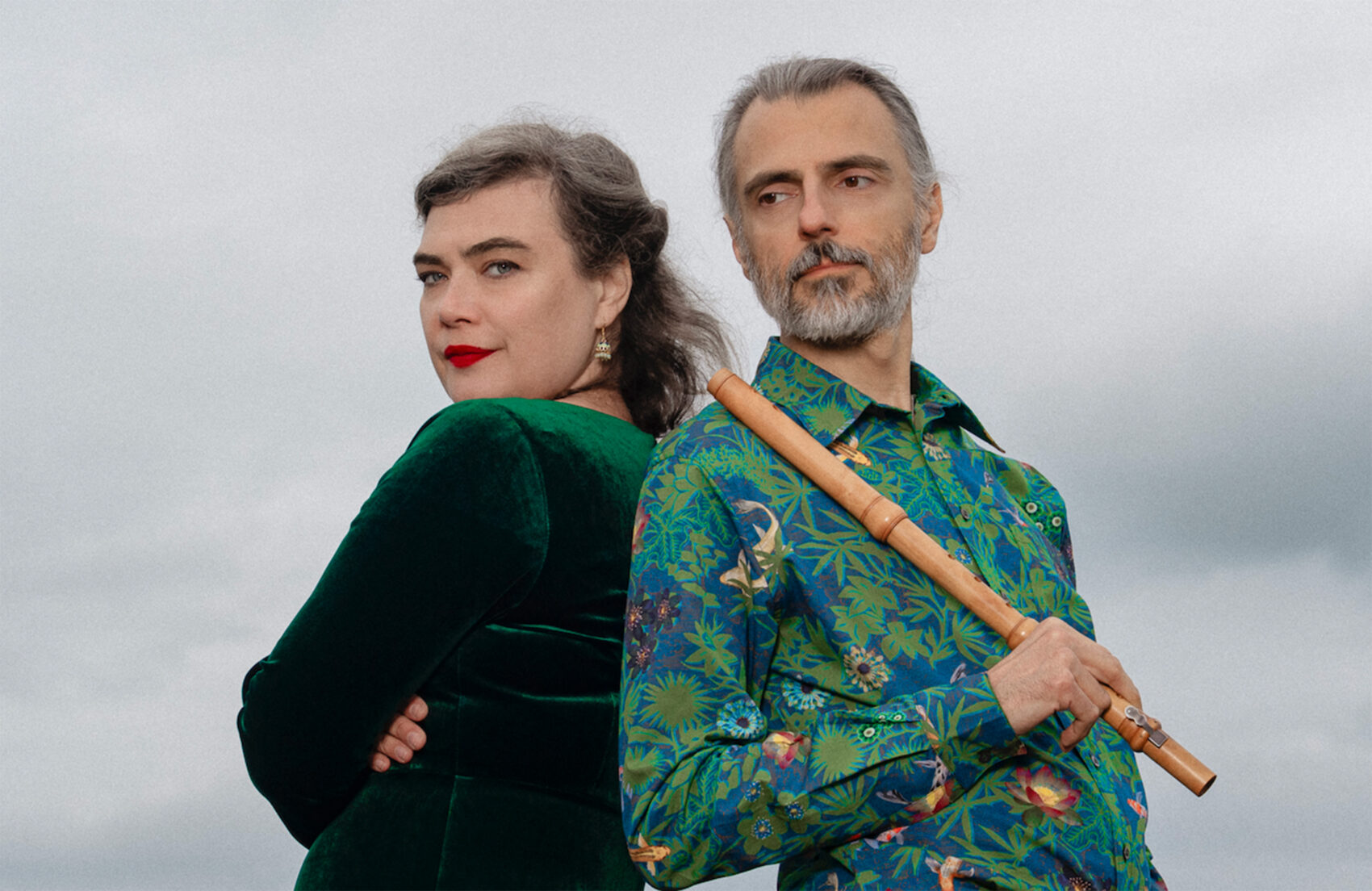 Portrait de Rosemary Standley et d'un flutiste avec une chemise verte à motif. ils sont dos à dos