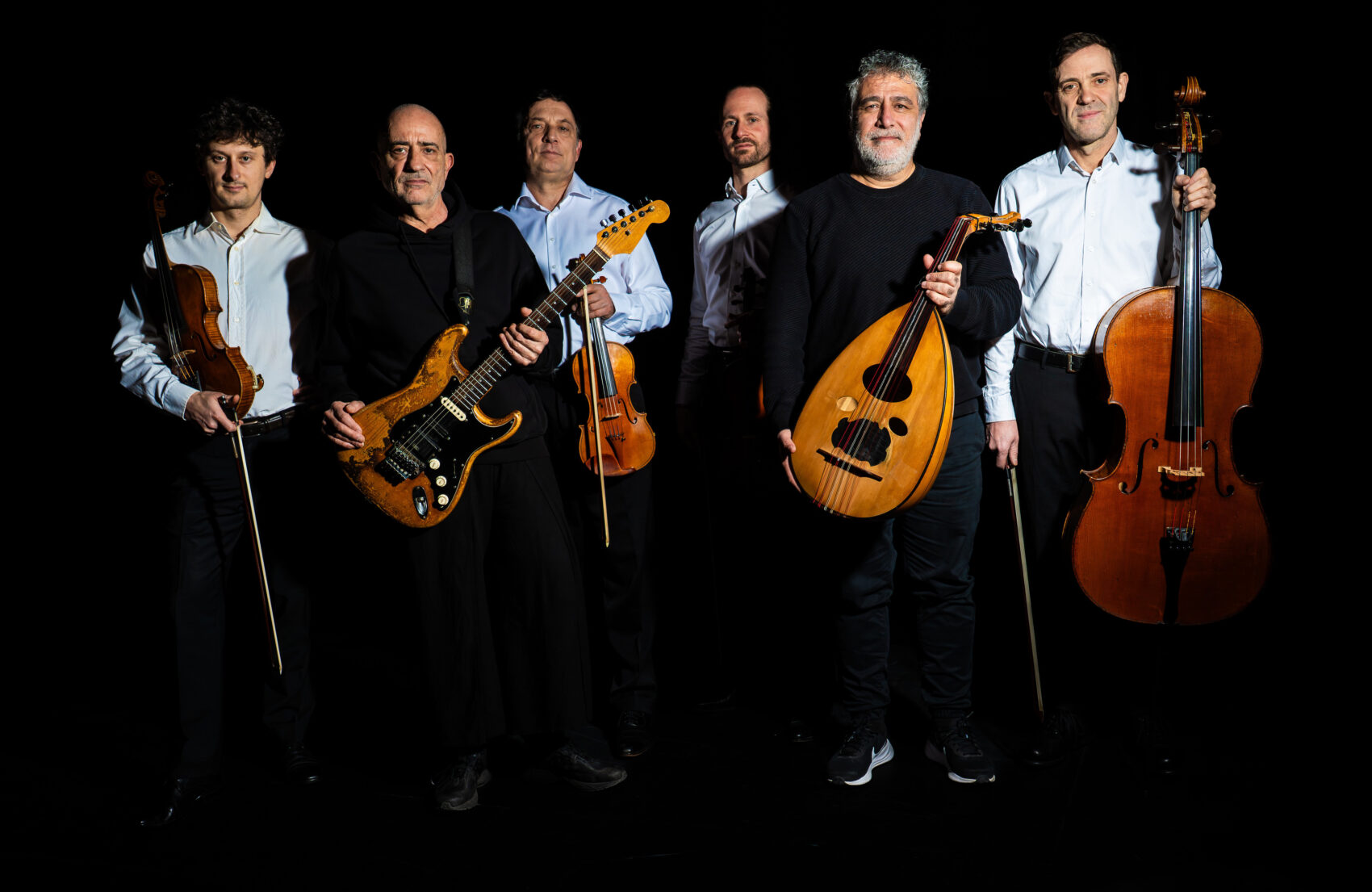 photo des quatre musiciens du quatuor en arrière plan avec des chemise blanche et du duo en premier plan en noir. Accompagnés de leur instrument à cordes