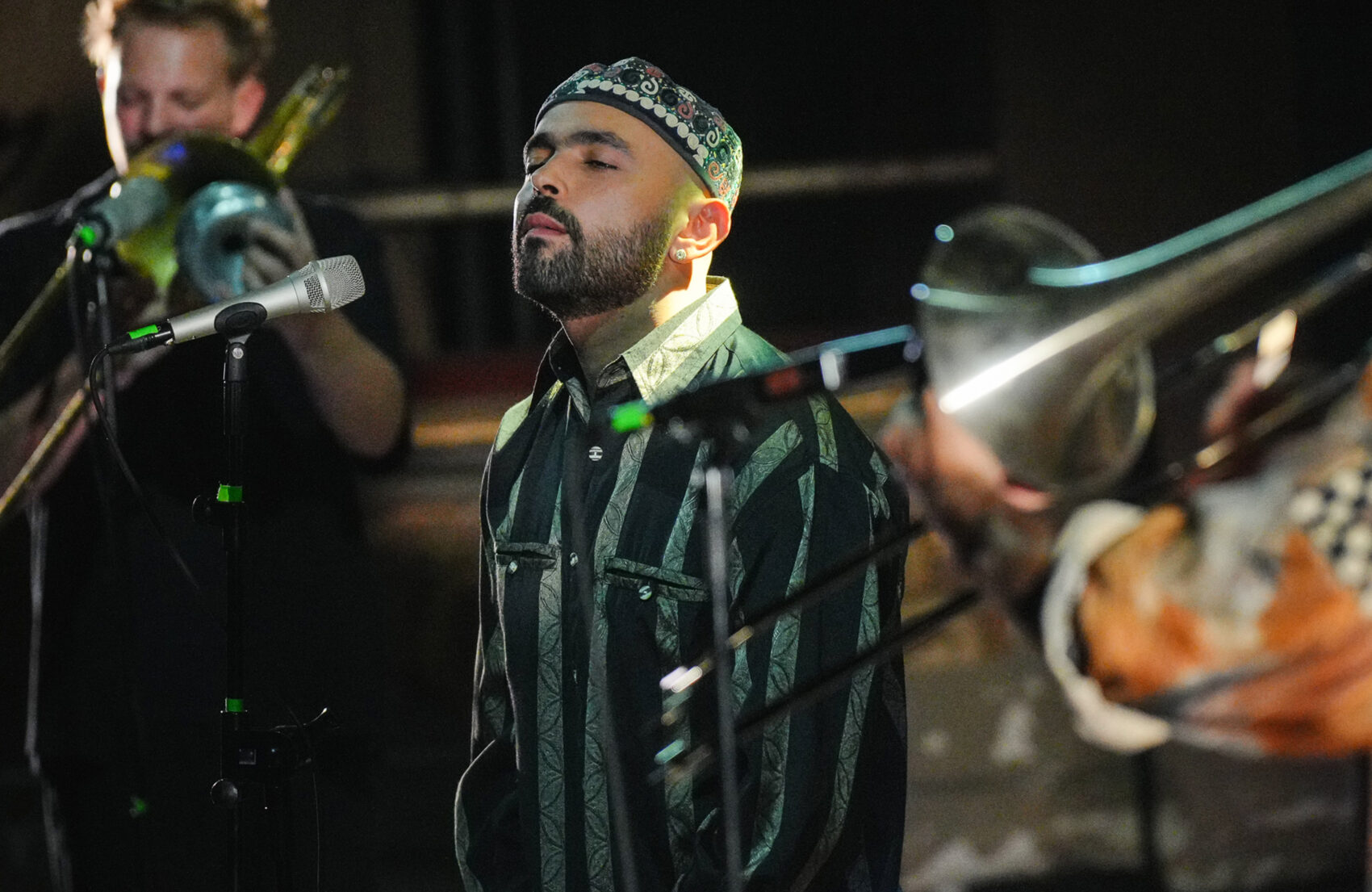 Portrait de l'artiste de profil, il ferme les yeux. Autour de lui, ses musiciens jouent du trombone