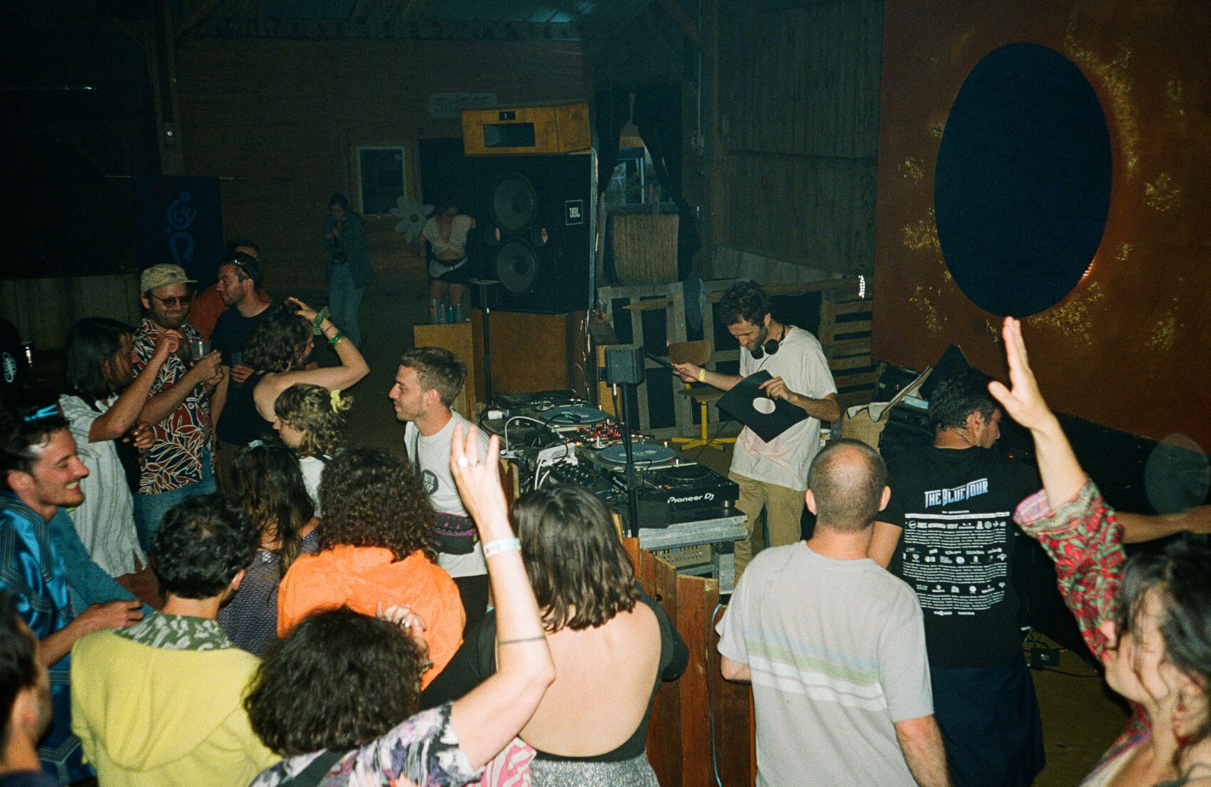 Photo de soirée avec des gens qui dansent devant un dj et des platines
